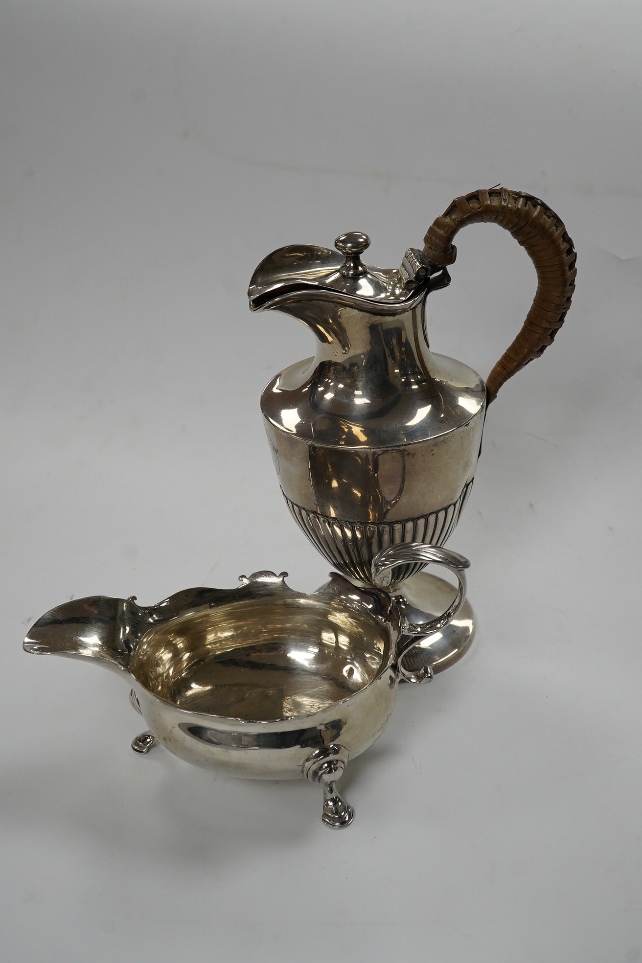 A George II small silver sauceboat, Gwillim & Castle, London, 1744, length 13.6cm, together with a George III silver hot water jug, London, 1791, gross 9.6oz. Condition - poor